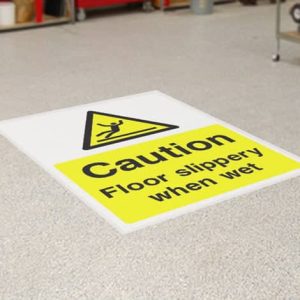 Caution floor sticker with bold, black and yellow diagonal stripes and the text 'Caution: Wet Floor' prominently displayed. Designed for high visibility in commercial or public areas to prevent slips and falls. Made of durable, slip-resistant vinyl with a strong self-adhesive backing for secure placement on various flooring surfaces.